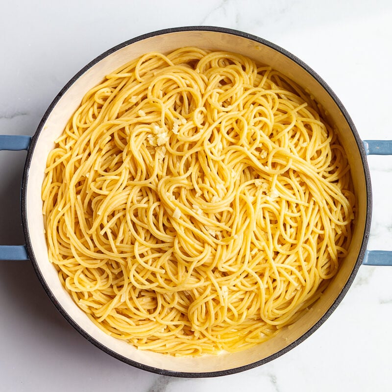 Spaghetti tossed in garlic butter and parmesan in a large pot, ready to serve.