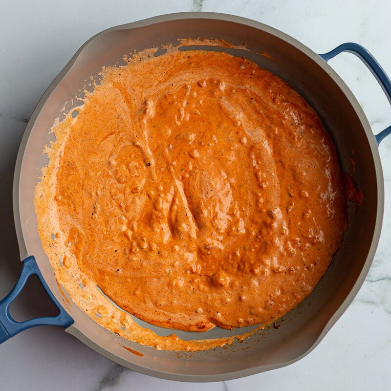 Creamy orange vodka sauce simmering in a skillet.