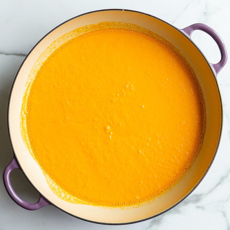 Creamy roasted red pepper pasta sauce simmering in a large skillet