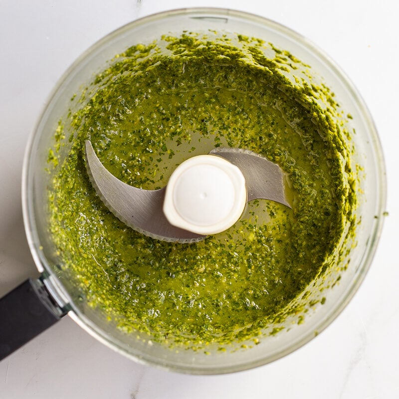 vegan pesto blended with olive oil, loose and glossy in a food processor