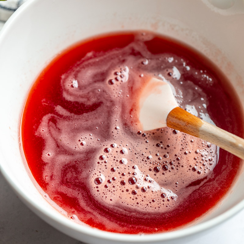 cooled strawberry juice in a white bowl being stirred