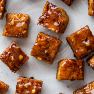 close up shot of baked tempeh covered in a teriyaki sauce