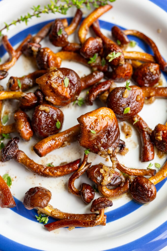 Close-up of caramelized chestnut mushrooms coated in garlic butter, garnished with fresh thyme sprigs