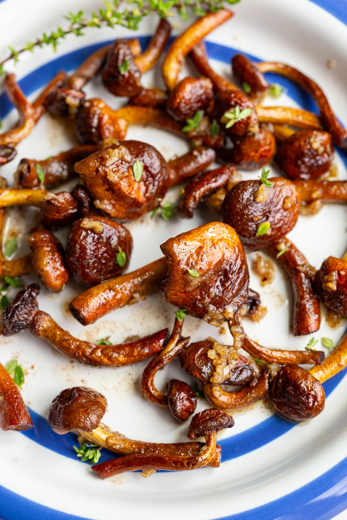 Close-up of caramelized chestnut mushrooms coated in garlic butter, garnished with fresh thyme sprigs