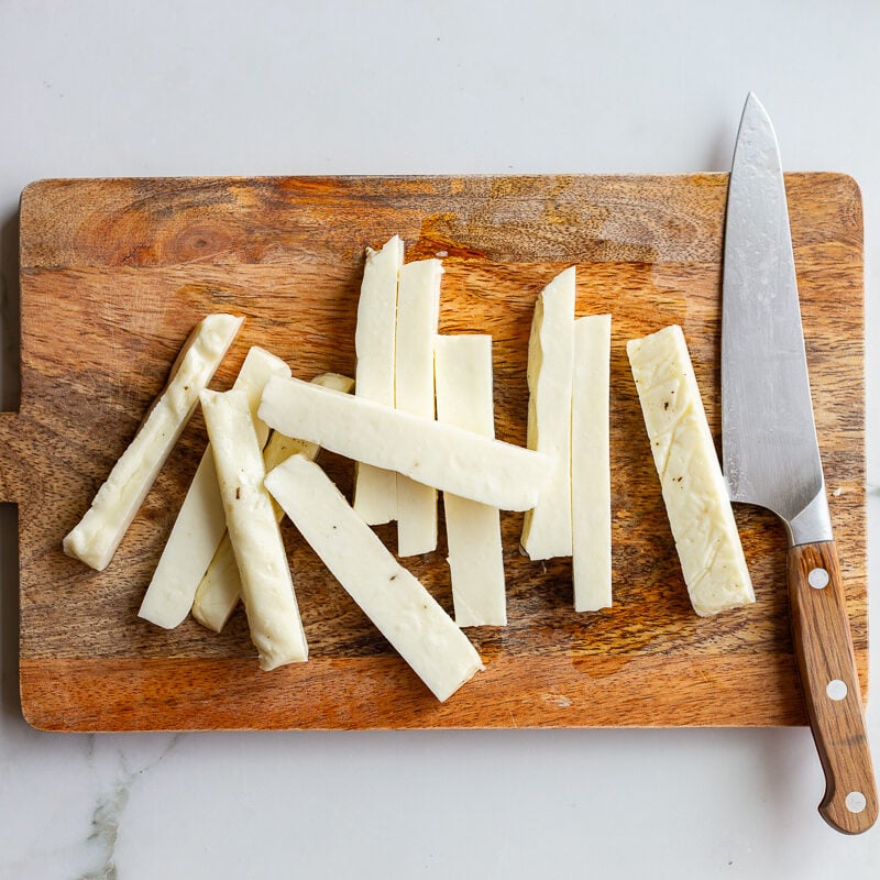 halloumi fries cut on a cutting board with a knife on the side