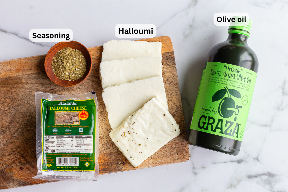 Overhead shot of grilled halloumi ingredients labeled on a wooden board, including halloumi cheese, seasoning, and olive oil