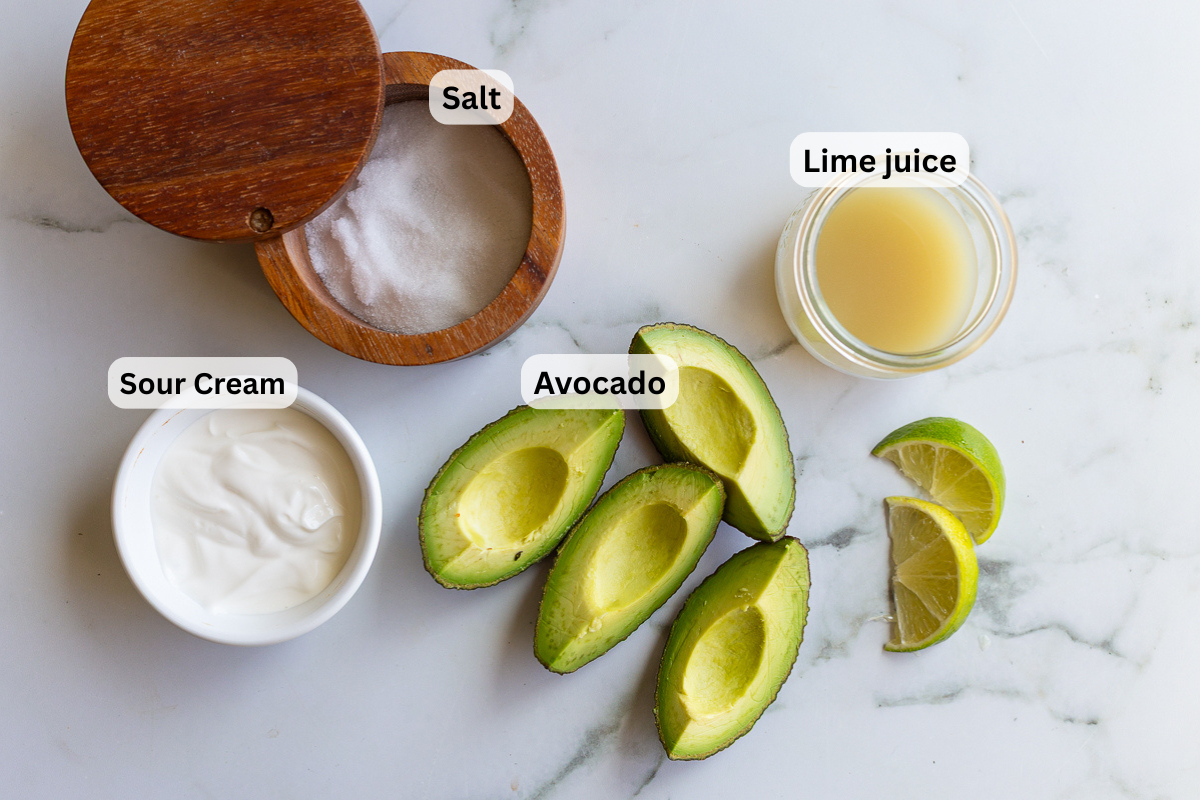 labeled ingredients needed to make avocado cream including sour cream, avocado, salt, and lime juice
