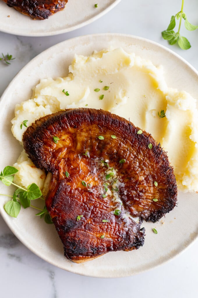 Close overhead shot of a golden-brown lion's mane steak with herb butter, served with mashed potatoes