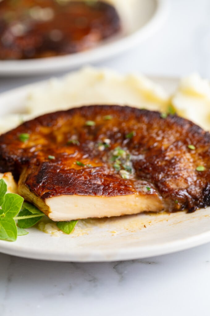 Close-up of a sliced lion's mane steak showing its dense, meaty white interior, served over mashed potatoes