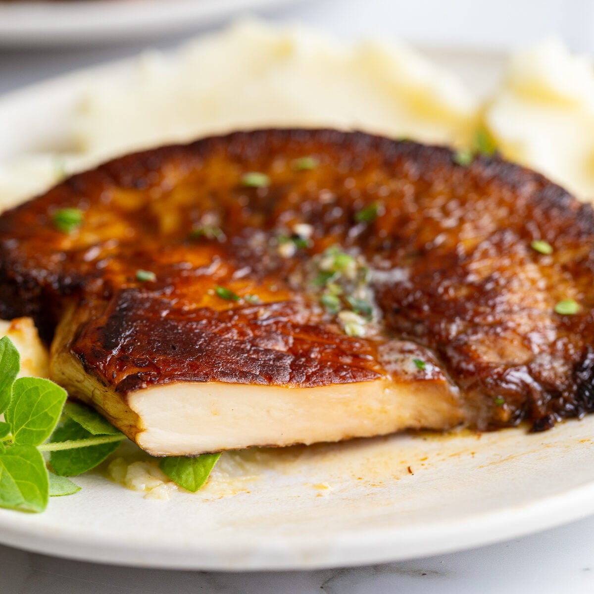 Close-up of a sliced lion's mane steak showing its dense, meaty white interior, served over mashed potatoes