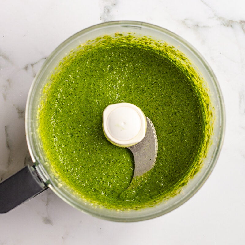 Blended walnut pesto in the food processor bowl before the olive oil is drizzled in