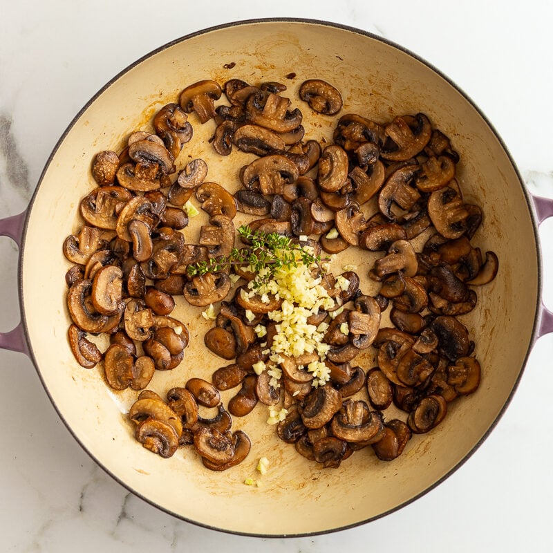 sauteed baby bella mushrooms in a skillet with garlic and herbs