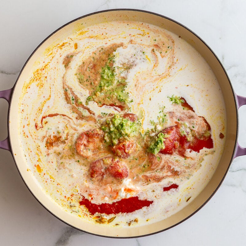 large skillet with tomato sauce, coconut milk, and cilantro blend