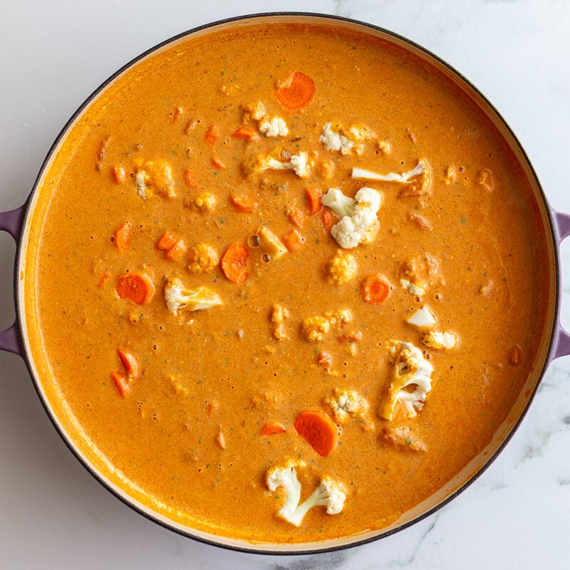 tikka masala sauce in a large skillet with cauliflower and carrots