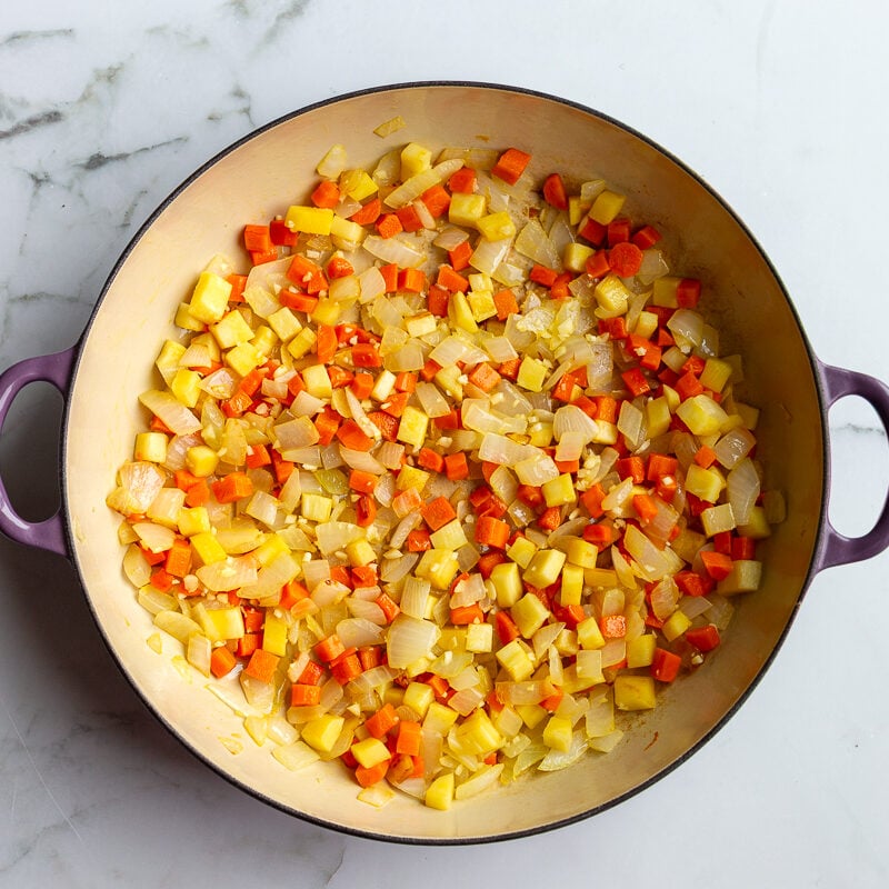 step 1 in making vegetarian shepherds pie: onion, parsnips, and carrots sauteed in a large skillet