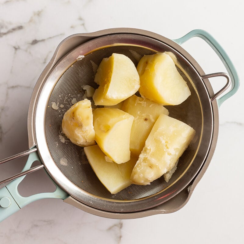 step 4 in making vegetarian shepherds pie: cooked potato chunks in a colander after being cooked