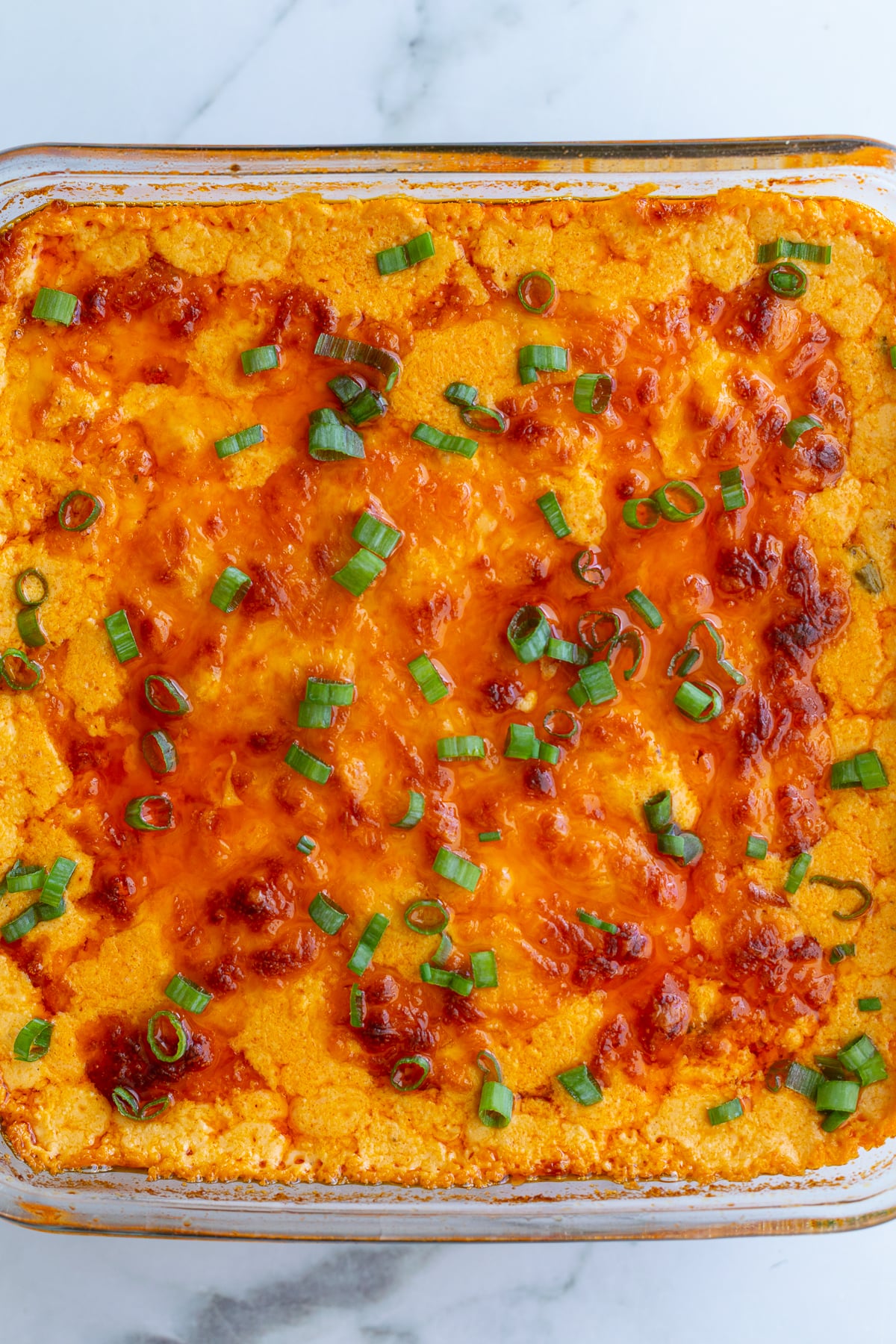 vegetarian buffalo dip in a glass baking dish with a golden cheesy topping