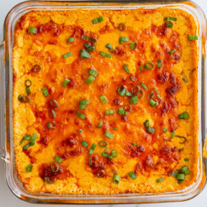 vegetarian buffalo dip in a glass baking dish with a golden cheesy topping