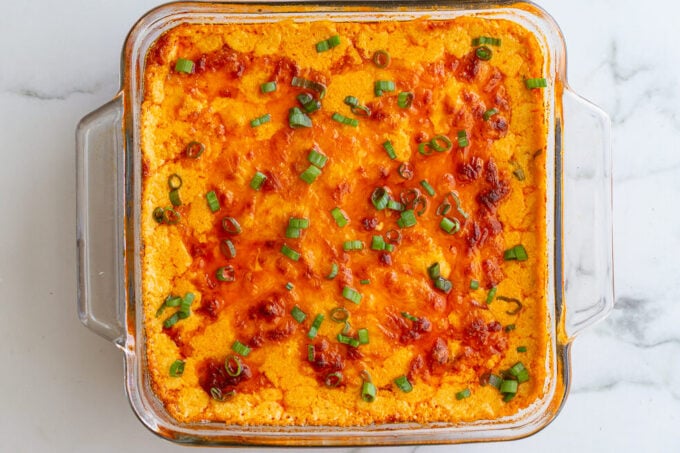 vegetarian buffalo dip in a glass baking dish with a golden cheesy topping