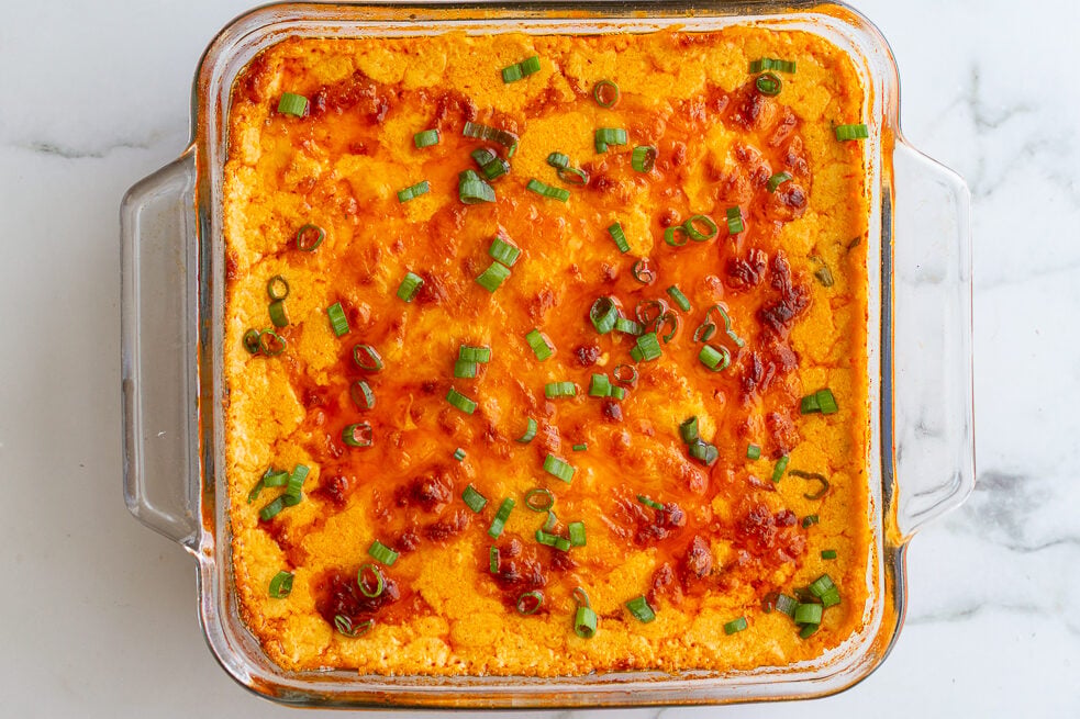 vegetarian buffalo dip in a glass baking dish with a golden cheesy topping
