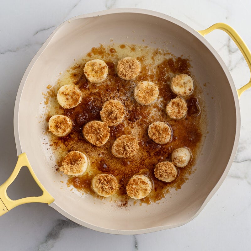 bananas and brown sugar in a yellow skillet to caramelize them