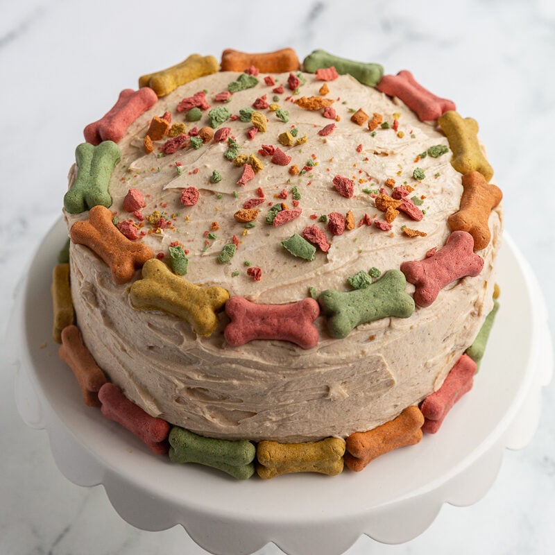 round dog birthday cake covered in colorful mini bones with crushed bones on top as if they're sprinkles