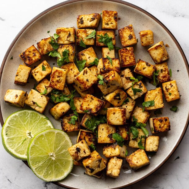 cilantro lime tofu cubes on a plate with a lime round on the plate