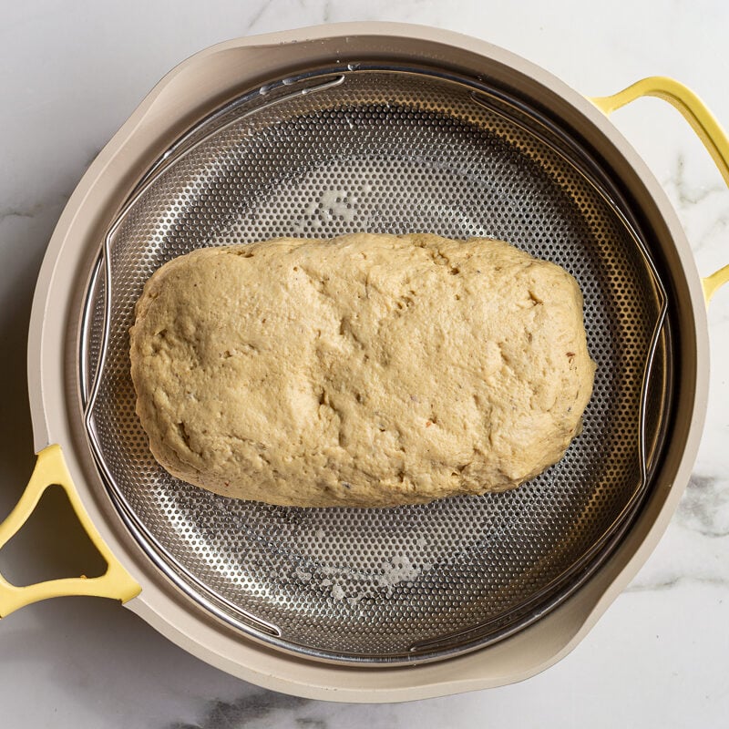 seitan steaming in a skillet in a steamer basket