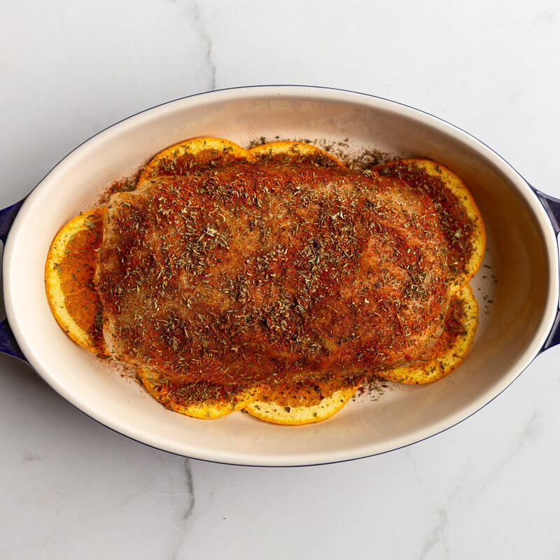 vegan turkey roast on a bed of orange slices laying in a pan