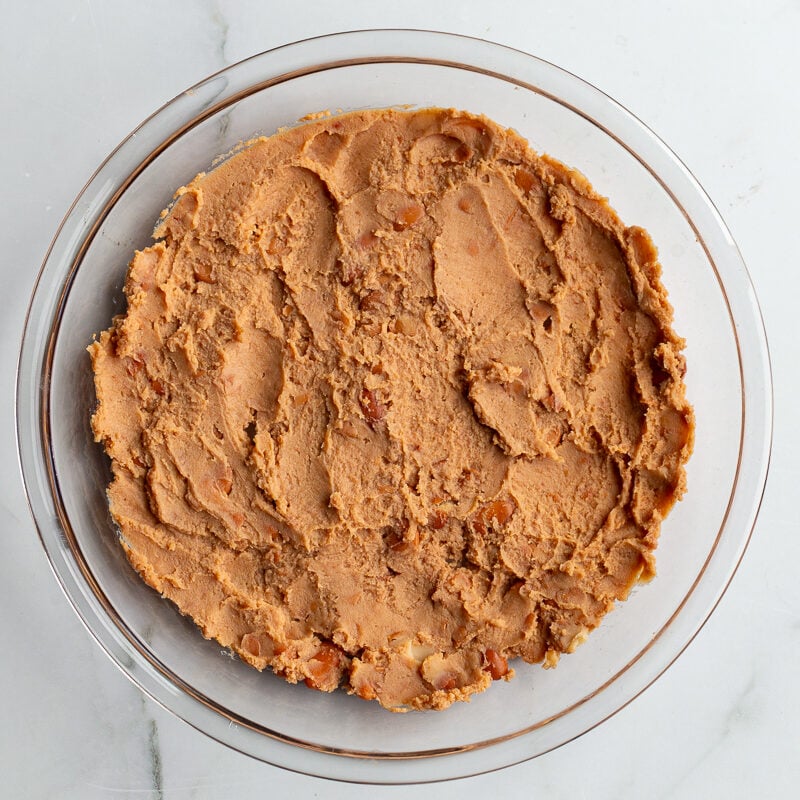 refried beans smeared in the bottom of a glass pie dish