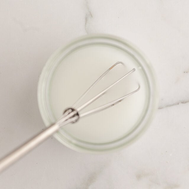 cornstarch slurry in a small glass dish with a small whisk in it