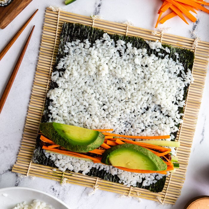 tofu sushi being assembled on a sushi mat