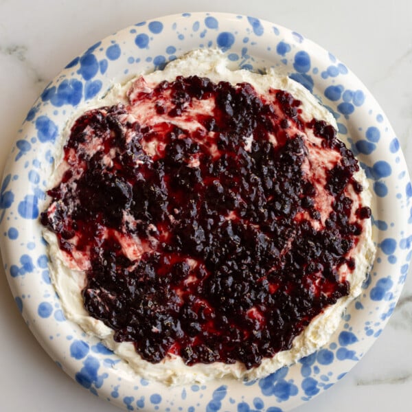 cream cheese and pepper jelly dip on a blue and white speckled plate