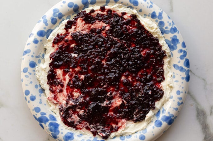 cream cheese and pepper jelly dip on a blue and white speckled plate