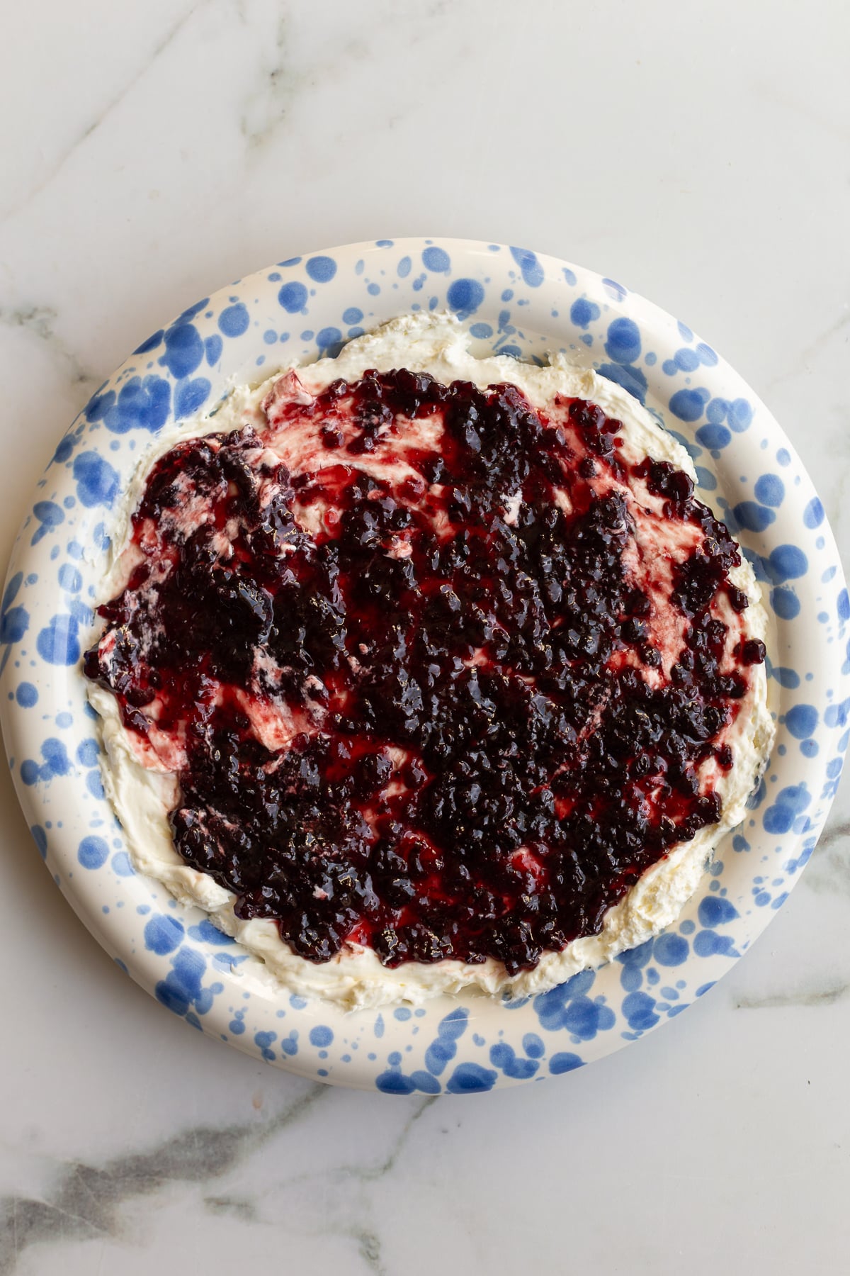 cream cheese and pepper jelly dip on a blue and white speckled plate