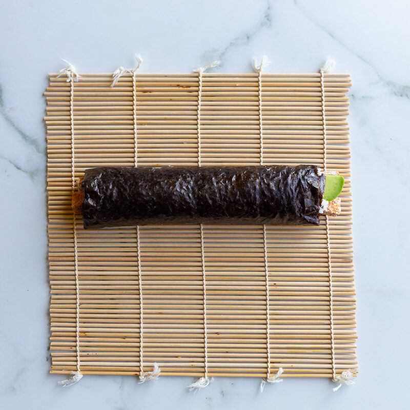 rolled up sweet potato sushi roll on a bamboo mat